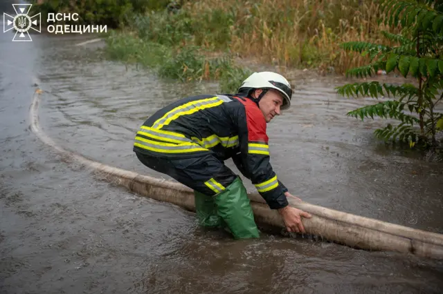 Рятувальник по лидки у воді тягне великий шланг для відкачування води