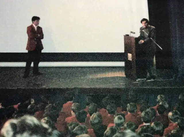 سنا، در سمت راست صحنه، در طول سفری که برای اقامت با واتکینز و خانواده‌اش داشت، با دانش‌آموزان مدرسه‌ای در اسکاتلند صحبت کرد