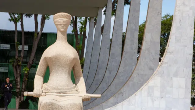 Fachada do palácio do Supremo Tribunal Federal, com a estátua da Justiça em frente, representada de olhos vendados e segurando uma espada no colo