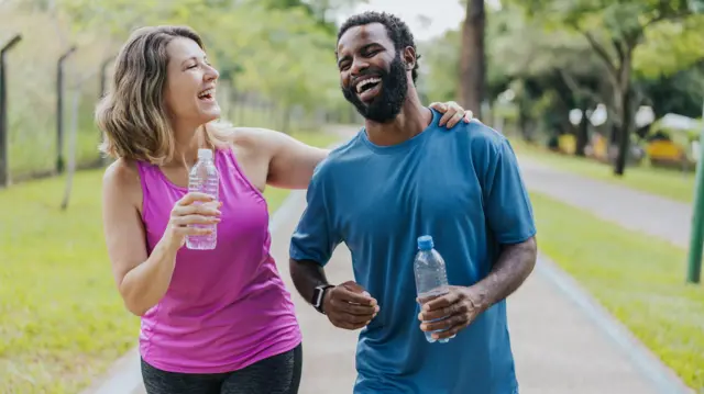 Mulher e homem sorriem durante caminhadainstant rouletteparque