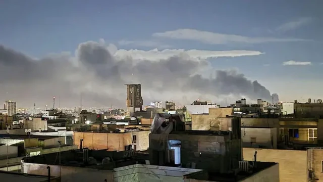 عکسی که از پشت بام خانه‌ای گرفته شده، نمایی از پشت بام‌ ساختمان‌های دیگر و دود ناشی از موشک باران