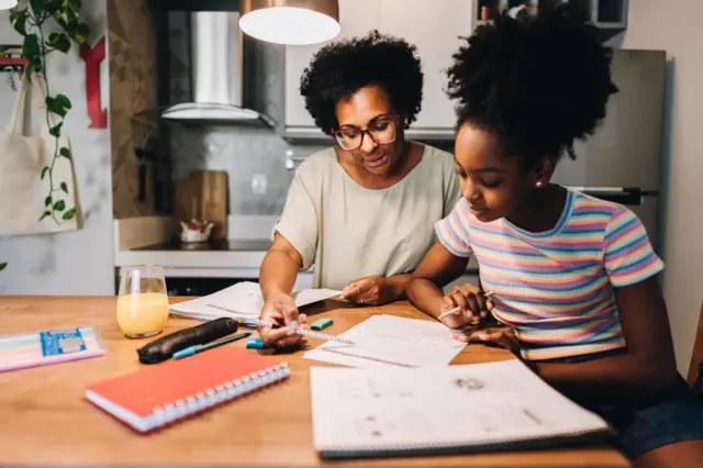 Mère aidant sa fille à faire ses devoirs dans la cuisine de l’appartement.
