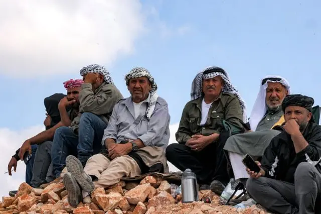 People gather to watch from a hilltop near Ofer military prison located between Ramallah and Beitunia in the occupied West Bank on October 13, 2025, ahead of the release of Palestinian prisoners in exchange for hostages held by Hamas in Gaza since the October 7 attacks. 