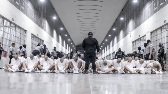 Hombres sentados en el suelo y policías rodeándolos en el Centro de Confinamiento del Terrorismo (CECOT), en El Salvador.