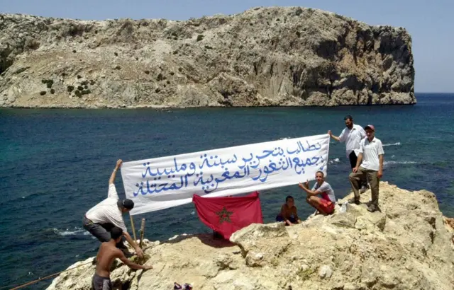 Manifestantes marroquíes ondean una pancarta que dice: "Exigimos la liberación de Ceuta y Melilla y de todos los territorios marroquíes ocupados", el 21 de julio de 2002, en la costa marroquí frente a la isla de Perejil.