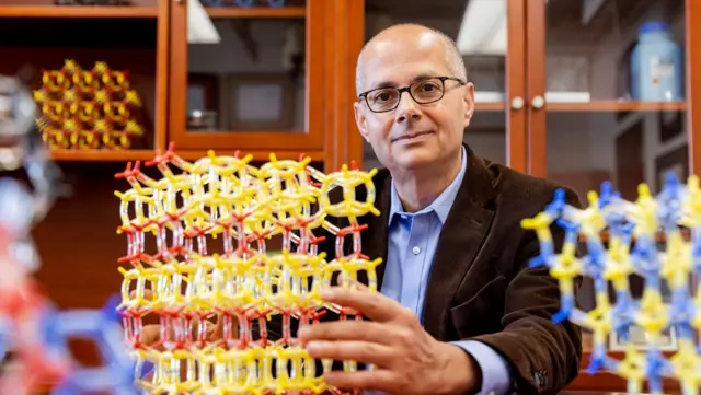 Omar Yaghi sentado con unas estructuras moleculares de colores.