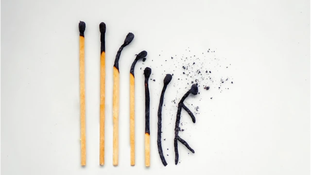 Gros plan sur des allumettes brûlées, classées de la plus grande à la plus petite, la dernière ayant la forme d'une personne symbolisant l'épuisement professionnel.