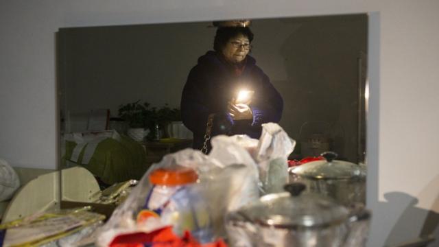 11月24日，60歲的王女士在北京周營一帶等待幫忙搬家的人。