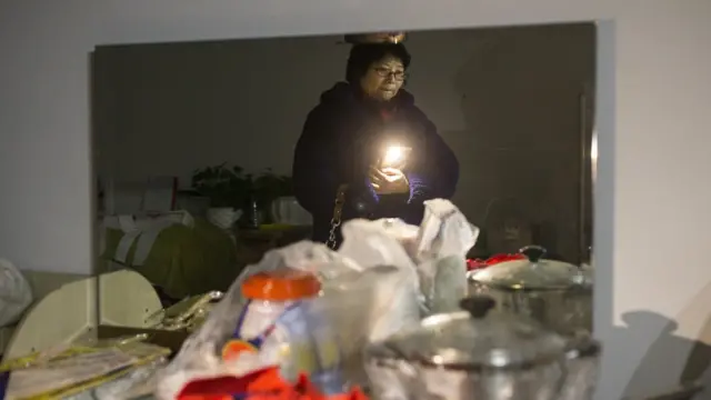 11月24日,60歲的王女士在北京周營一帶等待幫忙搬家的人。