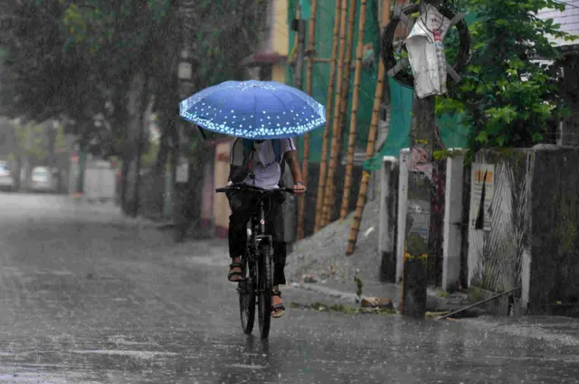বৃষ্টির মধ্যে একজন সাইকেল চালিয়ে যাচ্ছে 