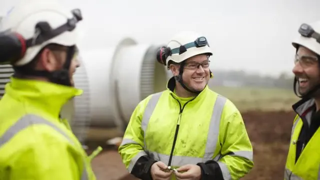 Des hommes en combinaison de travail et souriants