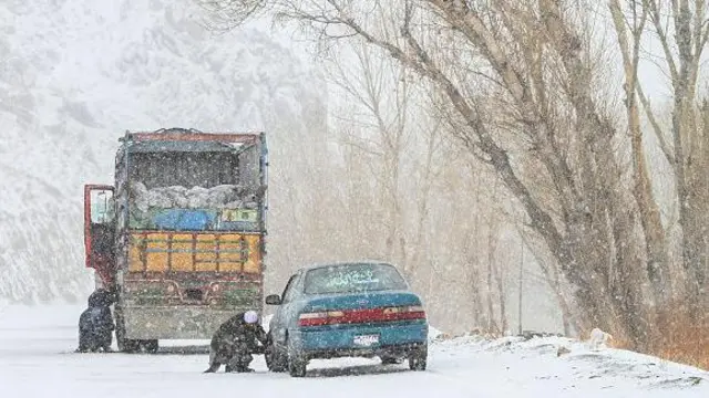 رانندگانی در ولایت بامیان، در حال نصب زنجیر چرخ بر اتومبیل خود هستند