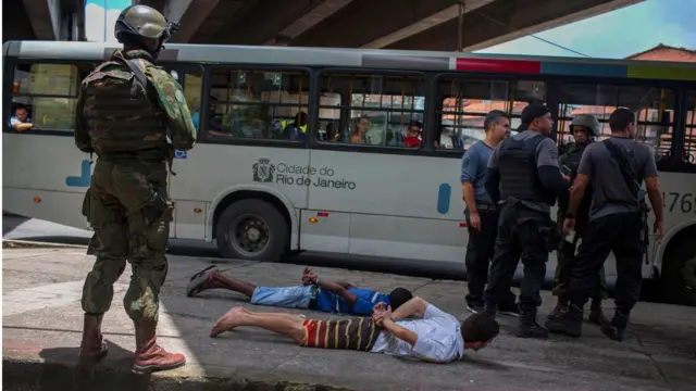 Militares e policiais fazem revistaaajogos cassinohomens, deitados no chão