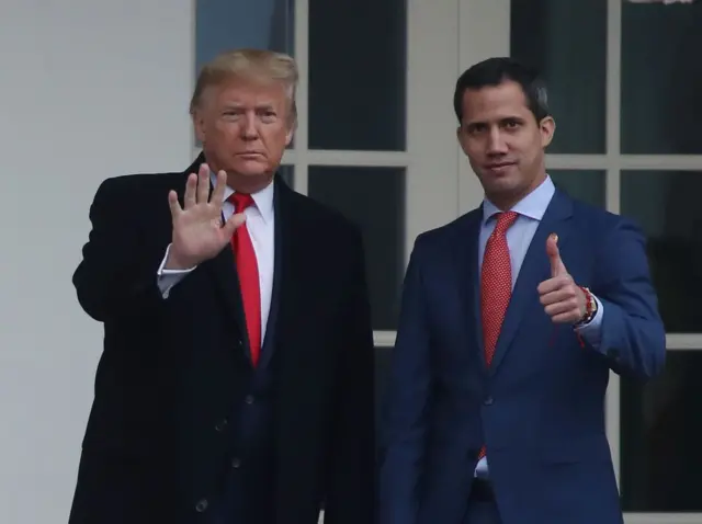Donald Trump y Juan Guaidó miran hacia el frente y saludan.