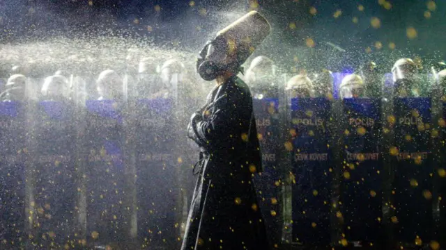 Seorang pengunjuk rasa berpakaian seperti Whirling Dervish disemprot merica oleh polisi di depan Aquaduct terkenal di Istanbul pada 23 Maret 2025.