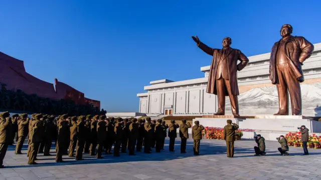 Pessoas saudando as estátuas de Kim Il-sung e Kim Jong-il em Pyongyang.