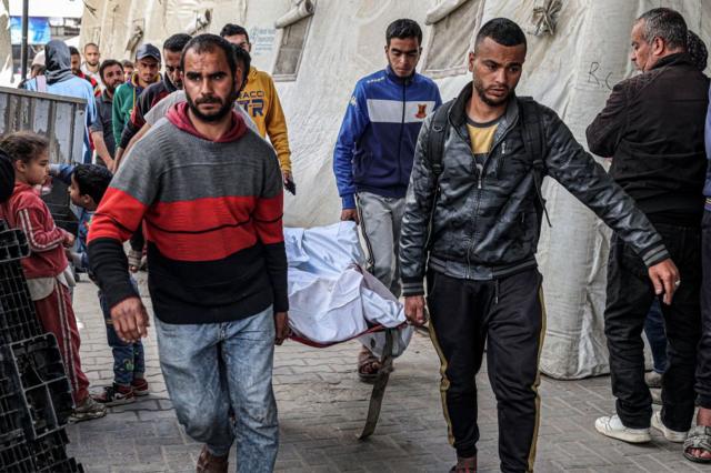 Unos hombres cargan en una camilla a una persona fallecida en un ataque israelí