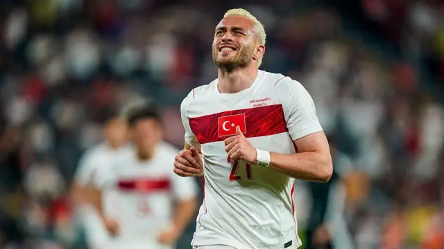 Kırmızı beyaz formalı futbolcu gülerek koşuyor