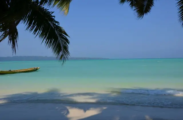 Arena, mar y loma con vegetación en la distancia