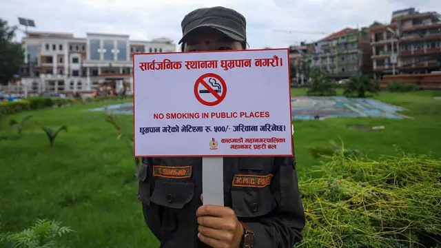धूमपानविरुद्ध सचेतना जगाउने प्लाकार्ड बोकेकी एक नगरप्रहरी