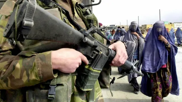 زنان افغان در حال عبور از کنار یک سرباز هلندی ناتو