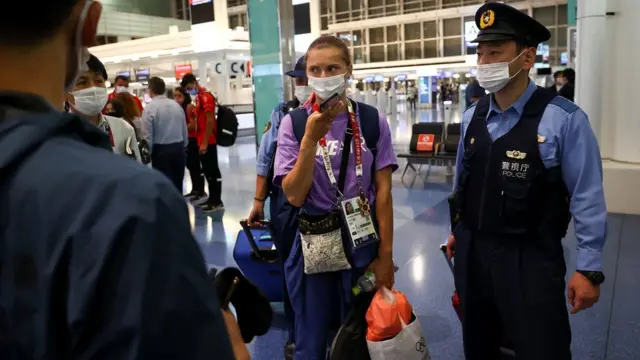 齐马努斯卡娅（中）在日本警视厅警员陪伴之下以手机与外界通话（1/8/2021）