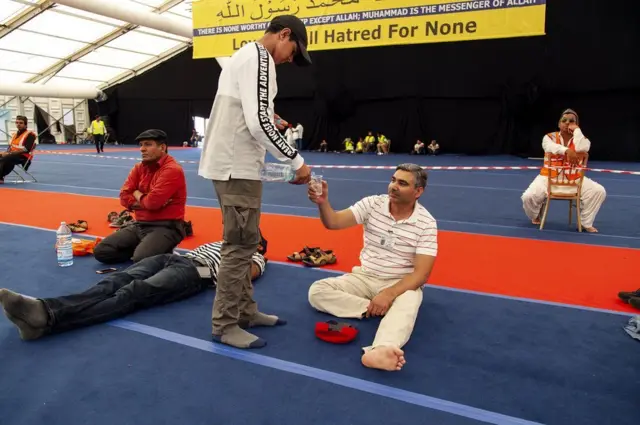 Tanweer membagikan air kepada peserta yang kepanasan dan kehausan.