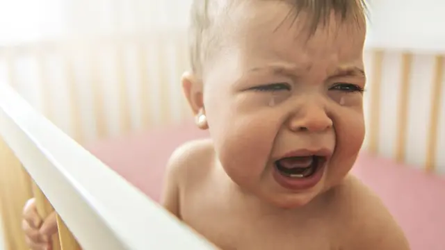 A baby in a cot crying