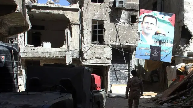 A man walks under a portrait of Syrian President Bashar al-Assad in a street inside the Yarmuk Palestinian refugee camp in the Syrian capital Damascus