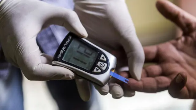 一名醫護人員在免費的逐戶篩檢活動中為病患進行血糖檢測。