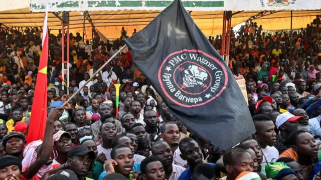 Grupo de manifestantes agitando uma grande bandeira preta com o logotipo do Wagner PMC, em Niamey, em 16 de setembro de 2023.