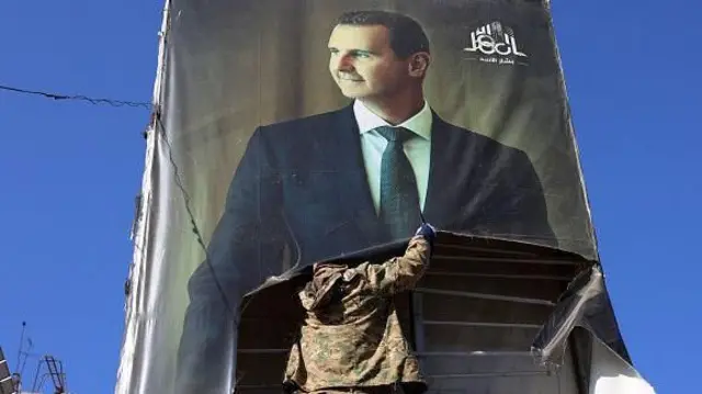 बशर अल असद के पोस्टर को फाड़ता विद्रोही