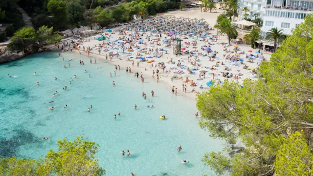 Praia de Maiorca, na Espanha, repleta de pessoas em dia de sol