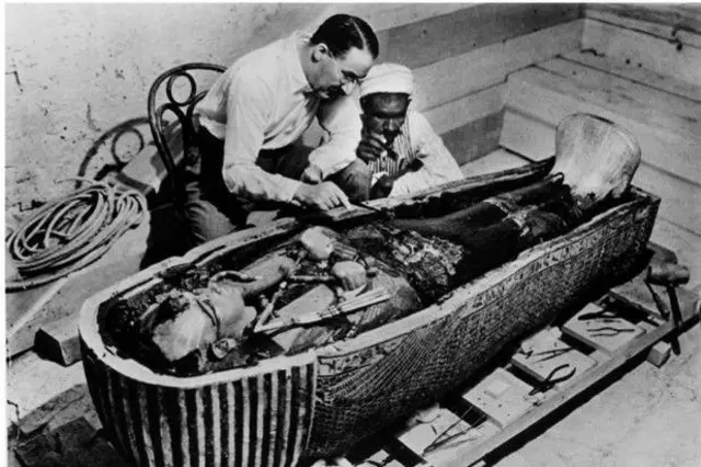 Howard Carter examine le cercueil de Toutankhamon.