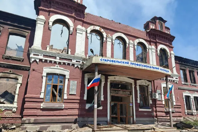 Фасад двухэтажного краснокирпичного здания с зияющими дырами на месте окон