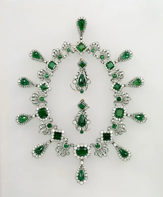 Un collar y unos aretes de plata con gemas verdes