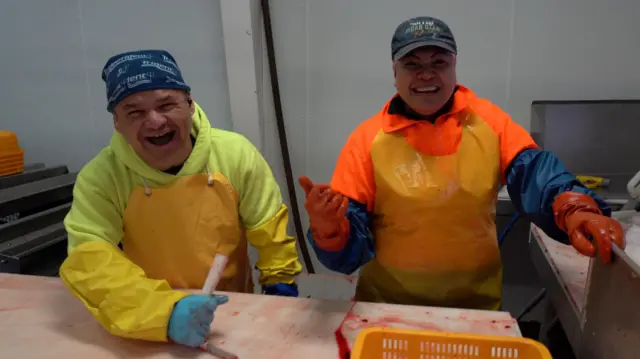 El mexicano Edgar Vega, ríe junto a una colega filipina en la planta de pescado en la que trabaja. 