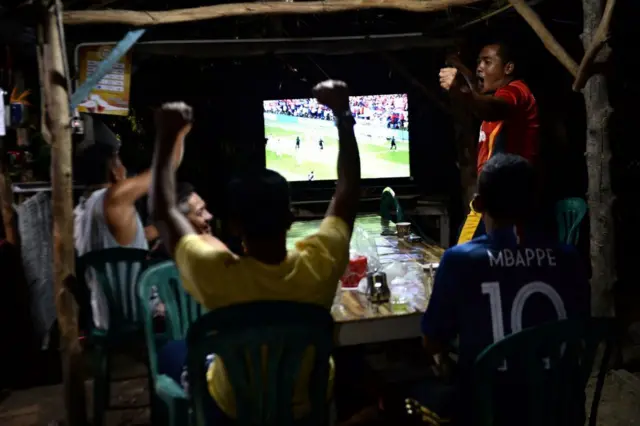 A group of Thai Muslim people cheer for France while watching a live television broadcast of the Russia 2018 World Cup final football match between France and Croatia at a coffeeshop in Thailand's southern province of Narathiwat on July 15, 2018. 