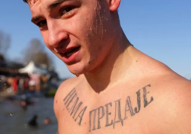 Српски православни верник са тетоважом на којој пише „Нема предаје“ излази након што је пливао за крст у леденим водама Дунава током прославе православног празника Богојављења у Београду