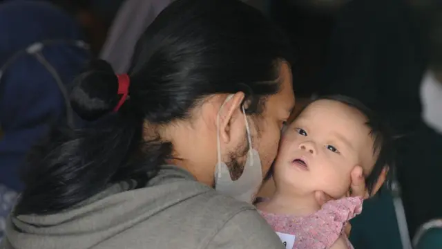 شخص يحمل طفلا مصابا بمتلازمة داون.