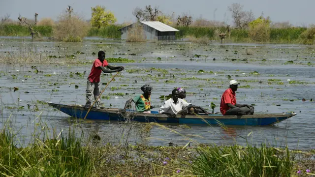 Des personnes déplacées passent devant une école submergée par les eaux de crue dans le village de Tong, à Bentiu.