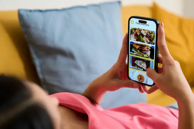 Mulher no sofá usando aplicativo de entrega de comida no smartphone