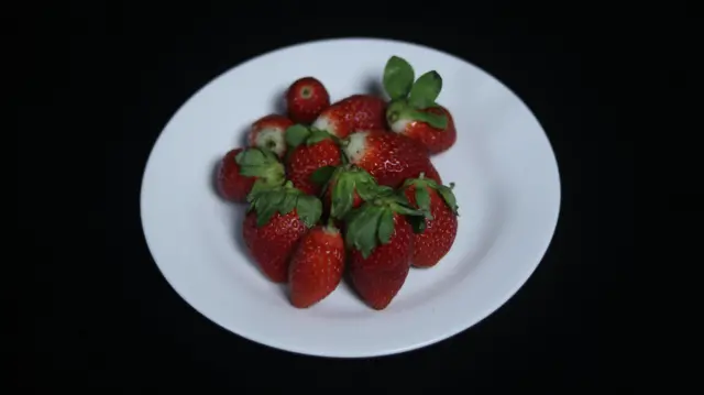 صورة تظهر ثمار الفراولة موضوعة داخل طبق أبيض اللون.