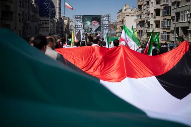 در یک راهپیمایی در تهران، تظاهرکنندگان حامی حکومت پرچم سوریه را حمل می‌کنند