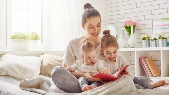 Madre leyéndole un cuento a dos niños.