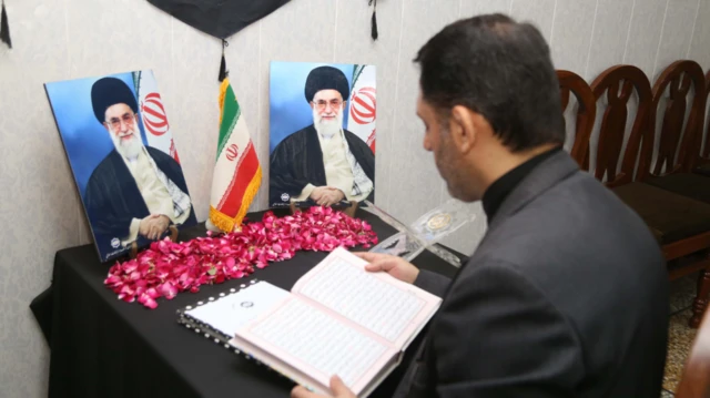 Un homme lit le Coran à côté des portraits du guide suprême iranien, l'ayatollah Ali Khamenei.