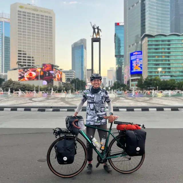 Ari Yami berpose dengan sepedanya di depan Bunderan HI, Jakarta Pusat.