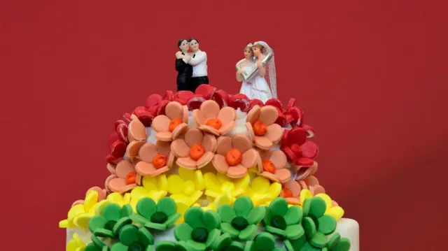 Um bolo de noiva com casais LGBTQ no topo