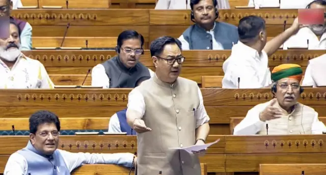 লোকসভায় সংসদ বিষয়ক মন্ত্রী কিরেন রিজিজু এক হাতে কাগজ ও অন্য হাত সামনে বাড়িয়ে কিছু বলছেন। পাশে বসে আছেন অন্য কয়েকজন এমপি। 