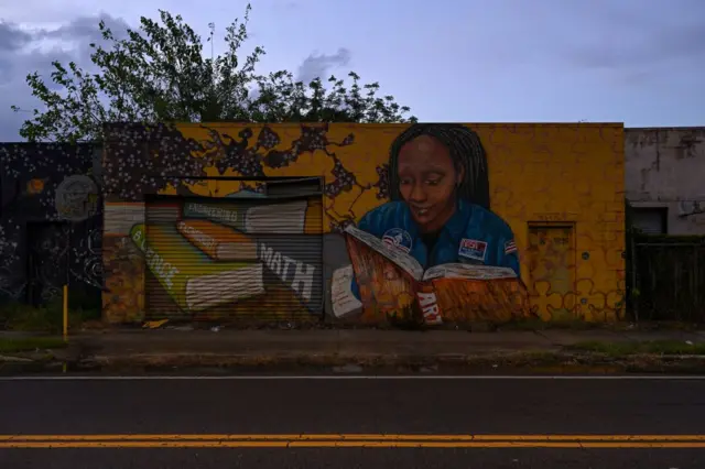 Un mural muestra a una mujer de color leyendo 